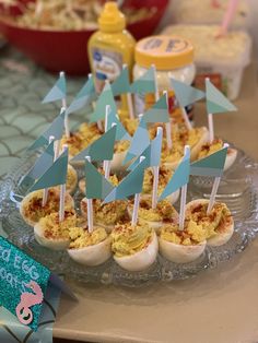 an assortment of deviled eggs with blue flags on them sitting on a glass platter