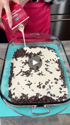 someone is spreading icing on a cake with white frosting and chocolate sprinkles