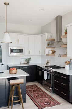 a kitchen with black cabinets and white counter tops, an area rug on the floor