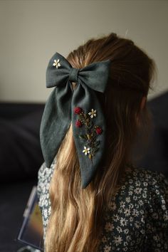 a woman with long hair wearing a green bow tie and flowers on it's head