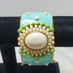 Adorn Your Wrist With The Vibrant Allure Of This Enamel Turquoise Bangle Bracelet. Crafted With Meticulous Detail, The Bracelet Showcases A Beautiful Turquoise Enamel Exterior, Accentuated By Intricate Green And Tan Beads For A Touch Of Natural Elegance. The Magnetic Closure Ensures Both Security And Ease Of Wear, Making It A Convenient Accessory For Any Occasion. Inside, A Lustrous Gold Finish Adds A Subtle Touch Of Glamour, Complementing The Vivid Turquoise Hues. With A Comfortable And Chic 1. Turquoise Bracelet Jewelry, Turquoise Bracelet Fashion Accessory, Turquoise Fashion Bracelet, Green Enamel Bangle, Adjustable Green Costume Jewelry Bracelets, Elegant Turquoise Bracelets, Bohemian Cream Bangle Jewelry, Bohemian Cream Bangle, Adjustable Turquoise Enamel Jewelry