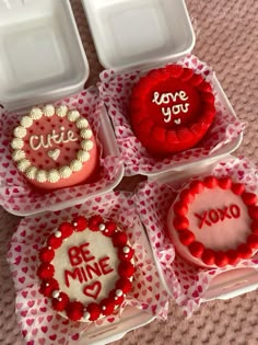 four valentine's day cakes in plastic containers on a table