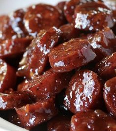 a bowl filled with cooked sausages covered in ketchup