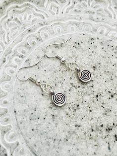 Experience the elegance of simplicity with these minimalist earrings featuring small silver swirls suspended from silver ear wires. Each pair captures the essence of contemporary chic and understated beauty. The delicate silver swirls add a touch of artistic flair to your everyday style, making them a versatile addition to your jewelry collection.  The spiral is a symbol of sacred geometry that represents continual growth, evolution, and transformation. It mirrors nature, from the unfolding of a fern frond to the galaxies spiraling in space. Spirals symbolize the journey from the center of being, expanding outward, and then returning to oneself, symbolizing both progress and a return to source. The spiral encourages us to embrace change, learn from our experiences, and strive for spiritual Minimalist Silver Swirl Earrings, Minimalist Sterling Silver Swirl Earrings, Nickel Free Silver Swirl Earrings, Hypoallergenic Sterling Silver Swirl Earrings, Minimalist Spiral Nickel-free Earrings, Nickel-free Spiral Minimalist Earrings, Minimalist Silver Spiral Earrings, Minimalist Swirl Earrings As Gift, Minimalist Swirl Earrings Gift