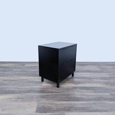 a black cabinet sitting on top of a hard wood floor next to a white wall