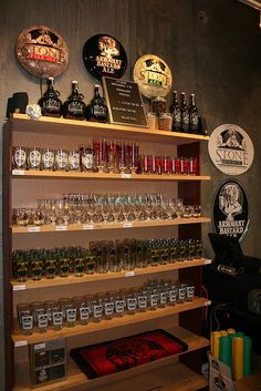 a shelf filled with lots of different types of alcohol bottles and glasses on top of wooden shelves