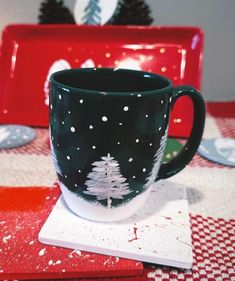 a coffee cup sitting on top of a red and white checkered tablecloth covered table