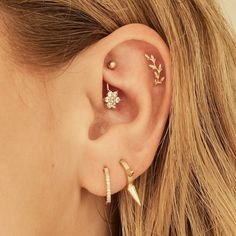 a close up of a person wearing ear piercings with gold leaves and stars on them