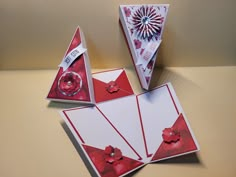 three red and white greeting cards on a table with a paper windmill in the background