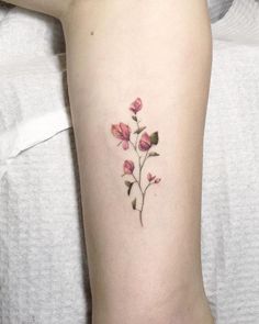 a small pink flower tattoo on the right arm