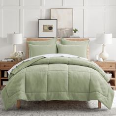 a bed with green bedspread and pillows in a white room next to a dresser