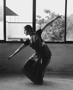 a woman standing on one leg in front of a window