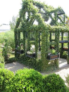 an outdoor garden with lots of plants growing on the walls and around it is a gazebo