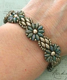 a close up of a person's arm wearing a bracelet with flowers on it