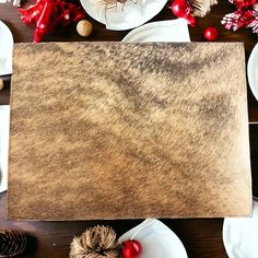 a table topped with plates and napkins covered in brown paper next to pine cones