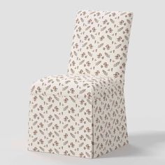 a white and brown chair with a flower pattern on the back, in front of a gray background