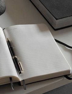 an open notebook sitting on top of a desk next to a pen