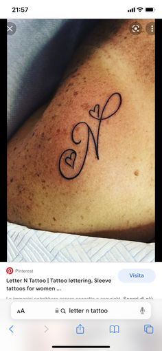 a tattoo on someone's arm with the letter n in cursive font