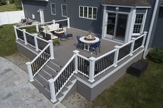 an aerial view of a deck with chairs and table in the foreground, next to a blue house