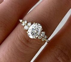 a woman's hand with a diamond ring on top of her finger and an engagement band