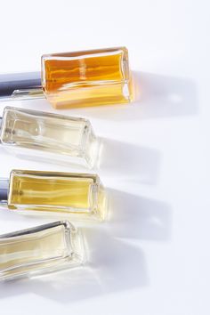 three different colored glass bottles sitting next to each other on top of a white surface