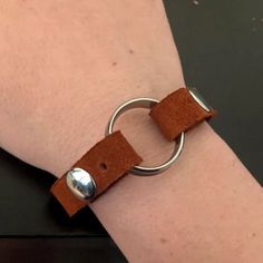 a close up of a person wearing a leather bracelet with a metal ring on it