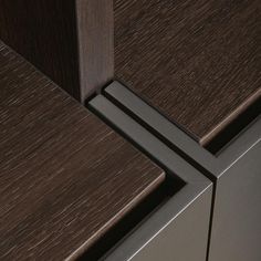 a close up view of the door handle on a wooden cabinet with dark wood grained finish