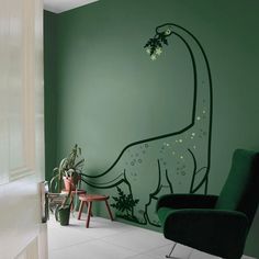 a green room with a dinosaur mural on the wall and a chair in front of it