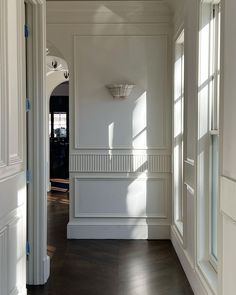 an empty hallway with white walls and wood floors