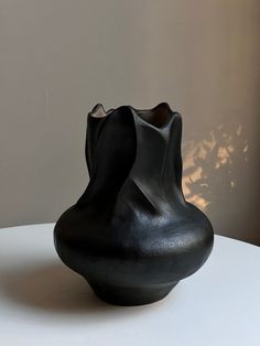 a black vase sitting on top of a white table