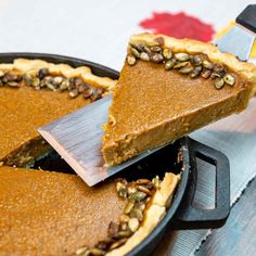 a slice of pumpkin pie is being cut with a large knife from the pie dish