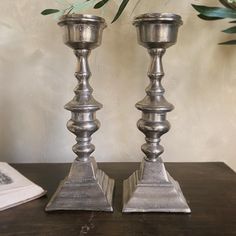 two metal candlesticks sitting on top of a wooden table