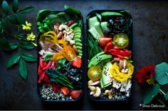 two trays filled with different types of vegetables and fruits on top of each other