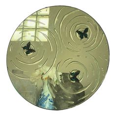 a glass plate with butterflies on it in front of a window and some vases