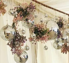 several disco balls hanging from the ceiling with flowers in them