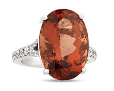 an oval shaped orange and white topazte ring with diamonds on the sides, set in