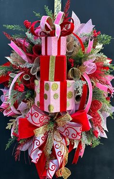 a christmas wreath with presents hanging from it's sides and ribbons on the front