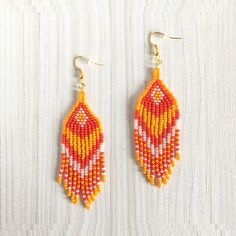 orange and yellow beaded earrings on white background