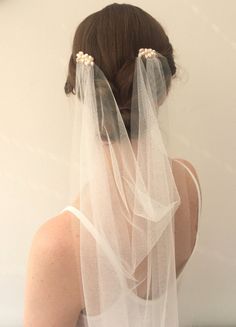 the back of a woman's head wearing a white veil with pearls on it