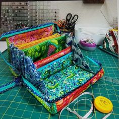 several pieces of colorful fabric sitting on top of a cutting board next to scissors and other crafting supplies