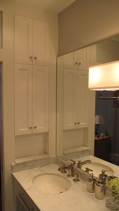 a bathroom with two sinks and white cabinets in it's own area, next to a large mirror