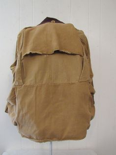 "Vintage 1930s or 40s hunting jacket. Made of khaki color herringbone twill cotton. Has a salt and pepper brown corduroy collar, tan corduroy cuffs, button front, five pockets, two shotgun shell pockets and a large back game pouch. Label reads: BLUE BILL BY THE MAKERS OF \"RED HEAD\". Size large. Actual measurements are: 46\" at the chest 48\" at the waist 21\" shoulder seam to shoulder seam 23\" shoulder seam to end of cuff 29.5\" overall length In very good condition with a 1\" hole at back an Vintage Brown Utility Jacket With Corduroy Collar, Vintage Brown Utility Jacket With Pockets, Vintage Cotton Utility Jacket With Flap Pockets, Vintage Brown Cotton Utility Jacket, Vintage Beige Cotton Utility Jacket, Khaki Cotton Utility Jacket For Hunting, Vintage Cotton Hunting Outerwear, Vintage Hunting Utility Jacket With Flap Pockets, 1940s Jacket