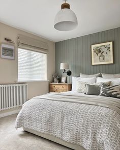 a bedroom with a bed, dresser and window in the corner next to a radiator