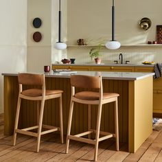 two wooden chairs sitting on top of a hard wood floor next to a kitchen island