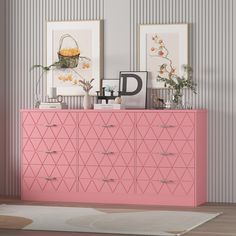 a pink dresser with two pictures on the wall behind it and a rug in front of it