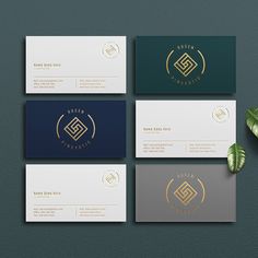 four business cards with gold foil on them and green leaves in the middle one has a logo