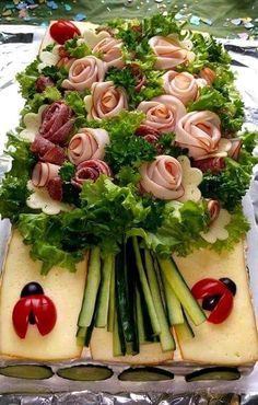 an arrangement of vegetables and meats is displayed on a cake sheet in the shape of a heart