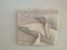 a sculpture of a dolphin on a white wall