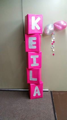 a pink block with the word delta spelled in white on it next to balloons and streamers