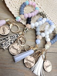 several different key chains with charms attached to them on top of a wooden table next to a straw hat